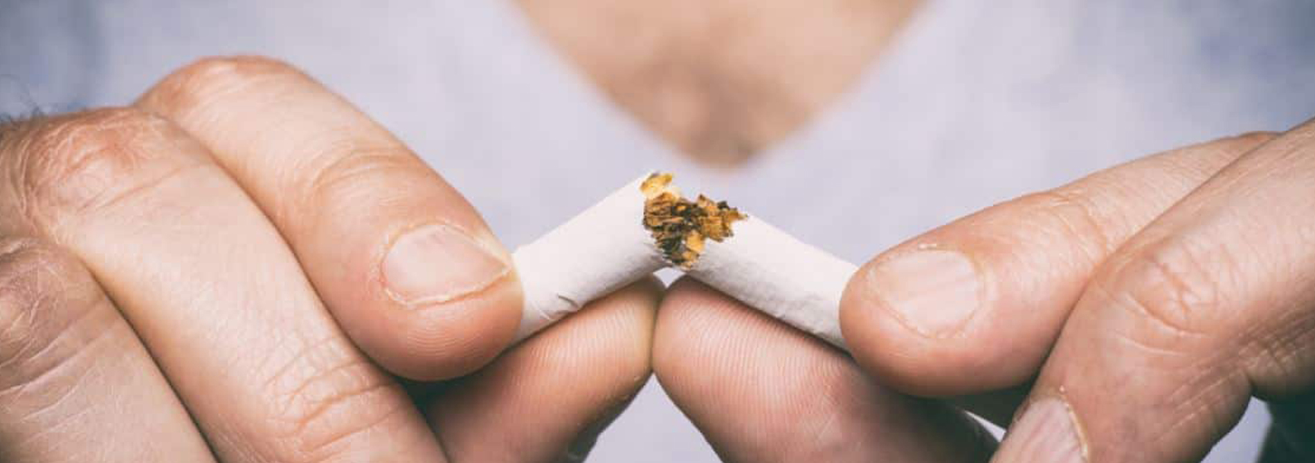 up close of hands breaking cigarette in half