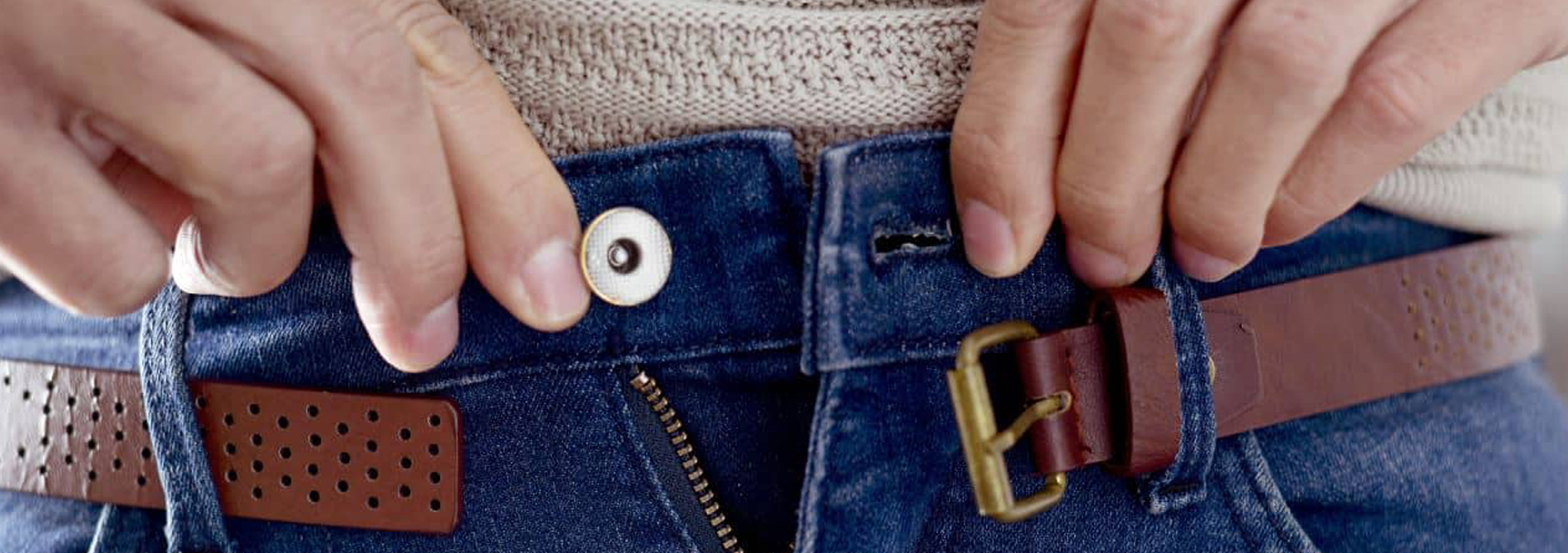 Up close of someone trying to close button on pants