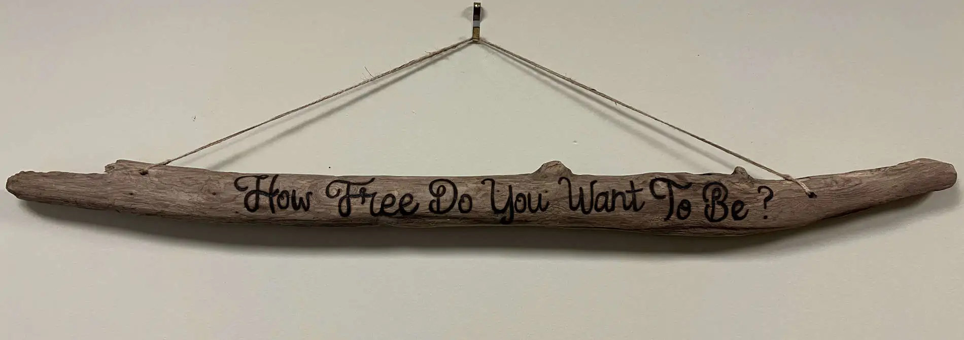 Driftwood art with "How Free Do You Want To Be?" engraved on it. Photo by Bart Ross