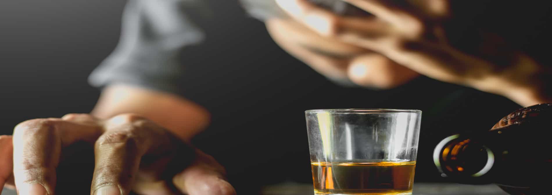 Man with head in hand and a drink in front of him.