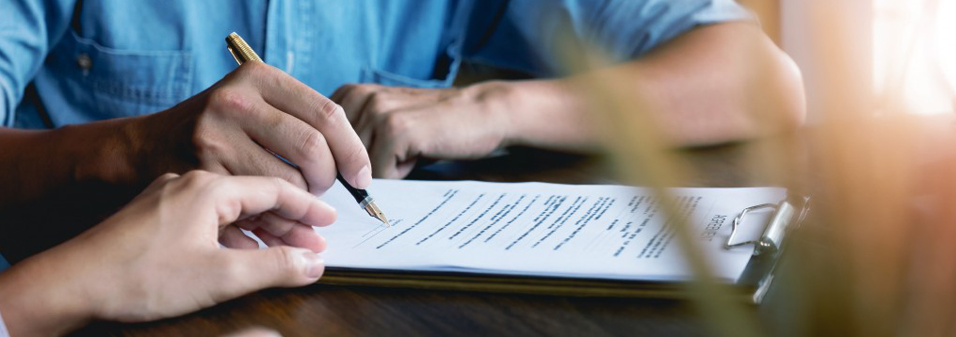 Man signing document and woman's hand touching his.